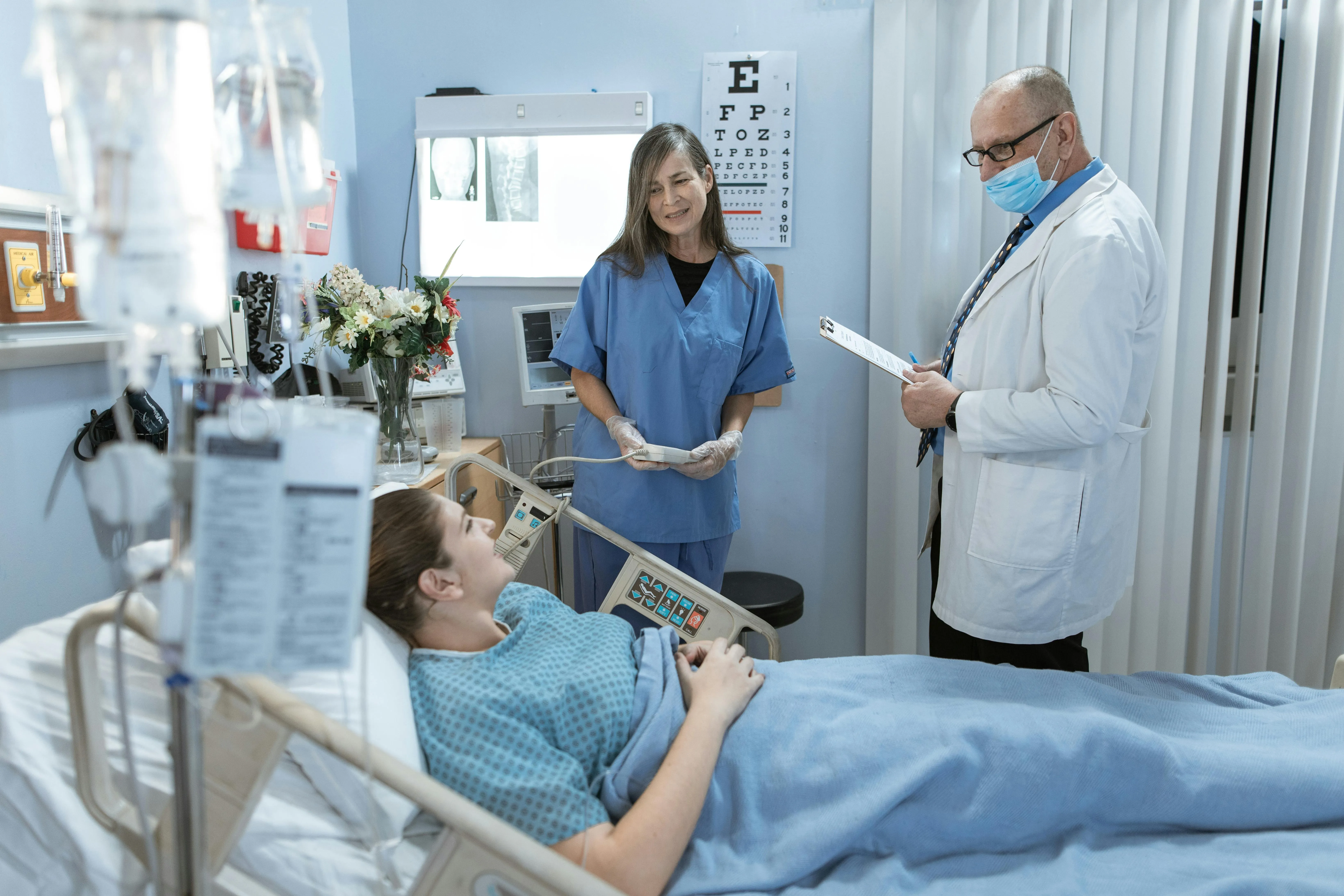 A doctor and nurse attending to a female patient in a hospital room.