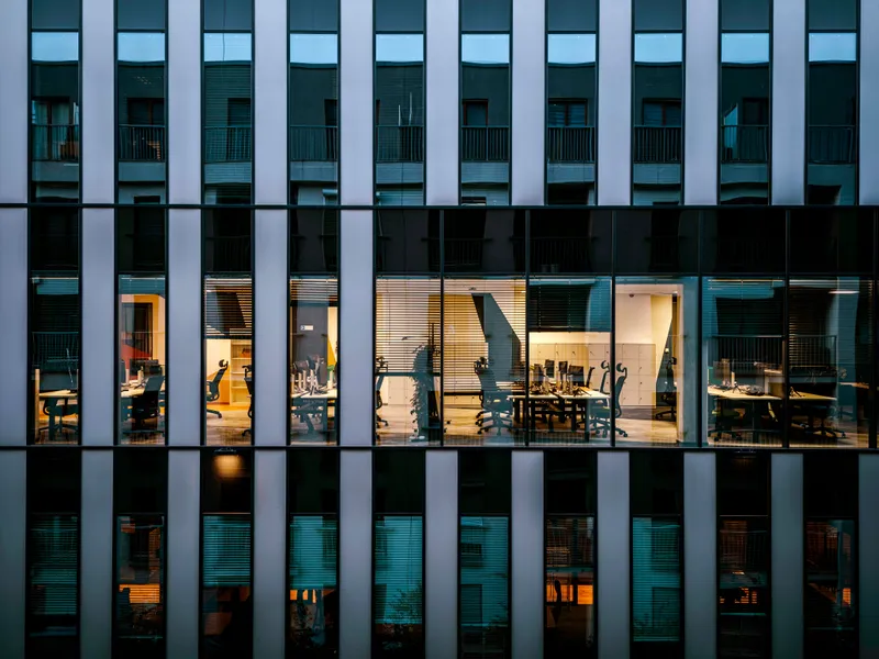 Illuminated&nbsp;office&nbsp;inside&nbsp;a&nbsp;modern&nbsp;glass&nbsp;building&nbsp;exterior,&nbsp;showcasing&nbsp;architecture&nbsp;and&nbsp;workspace&nbsp;design.