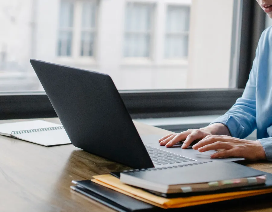 Professional desktop with laptop, notebook, and phone in natural daylight