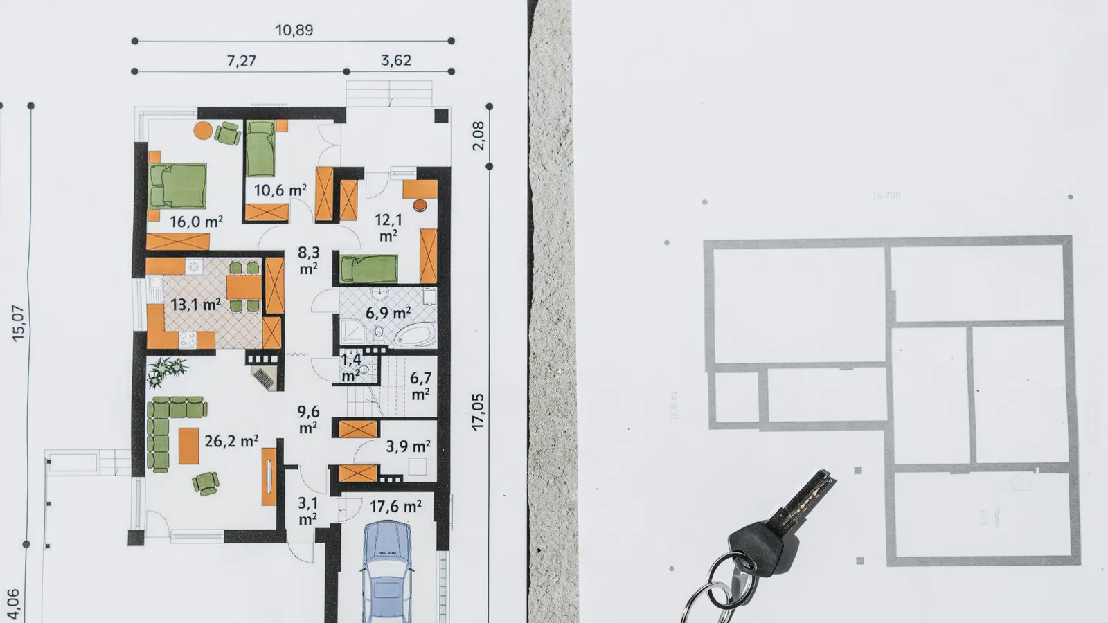 House plans, notebook, keys, and a laptop arranged on a sunlit table