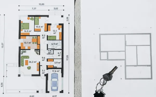 House plans, notebook, keys, and a laptop arranged on a sunlit table