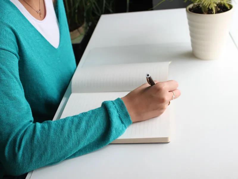 Student organizing a planner, notes, and laptop at a desk