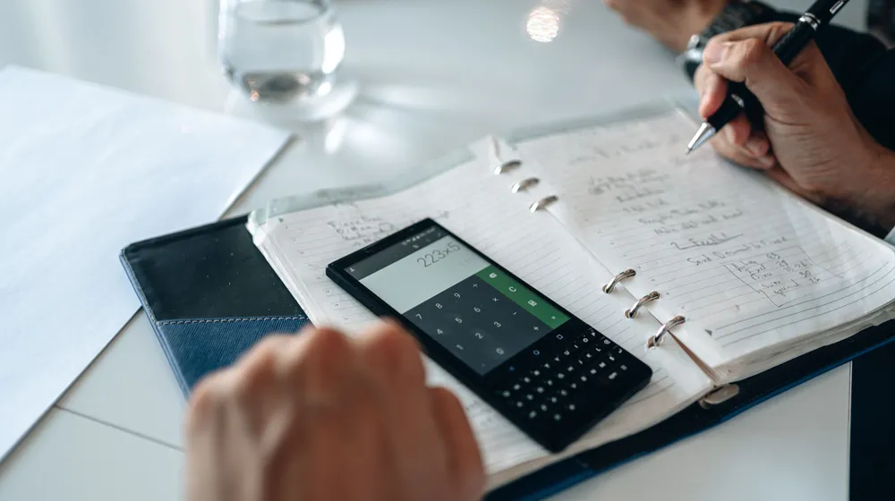 A desk with a calculator and notebook