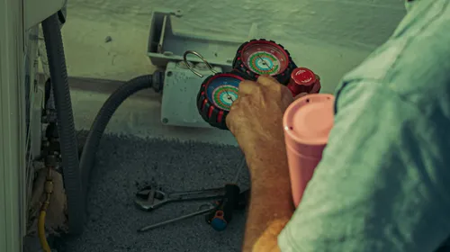 A&nbsp;technician&nbsp;checks&nbsp;and&nbsp;repairs&nbsp;an&nbsp;HVAC&nbsp;system&nbsp;outdoors&nbsp;using&nbsp;tools&nbsp;and&nbsp;gauges.