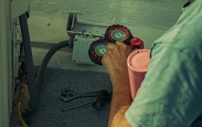A&nbsp;technician&nbsp;checks&nbsp;and&nbsp;repairs&nbsp;an&nbsp;HVAC&nbsp;system&nbsp;outdoors&nbsp;using&nbsp;tools&nbsp;and&nbsp;gauges.