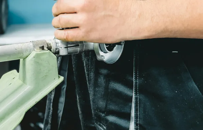 Close-up&nbsp;of&nbsp;a&nbsp;plumber&nbsp;in&nbsp;blue&nbsp;uniform&nbsp;working&nbsp;on&nbsp;a&nbsp;pipe&nbsp;repair&nbsp;with&nbsp;a&nbsp;wrench.