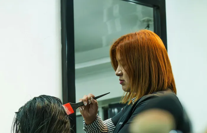 A&nbsp;stylist&nbsp;applies&nbsp;hair&nbsp;color&nbsp;to&nbsp;a&nbsp;client&nbsp;in&nbsp;a&nbsp;modern&nbsp;salon&nbsp;setting.