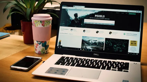 A&nbsp;tidy&nbsp;desk&nbsp;setting&nbsp;with&nbsp;a&nbsp;laptop&nbsp;showing&nbsp;a&nbsp;stock&nbsp;photo&nbsp;website&nbsp;and&nbsp;a&nbsp;smartphone.