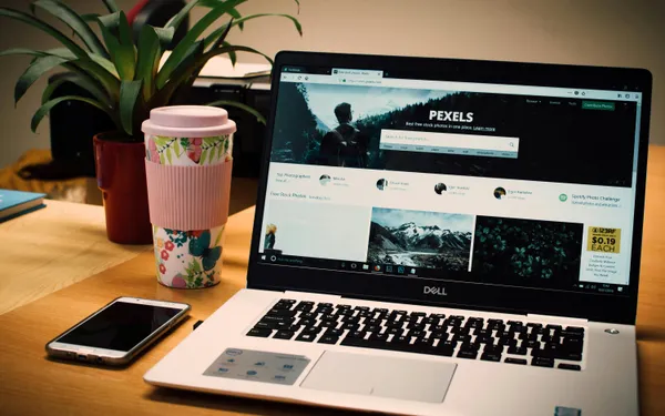 A&nbsp;tidy&nbsp;desk&nbsp;setting&nbsp;with&nbsp;a&nbsp;laptop&nbsp;showing&nbsp;a&nbsp;stock&nbsp;photo&nbsp;website&nbsp;and&nbsp;a&nbsp;smartphone.