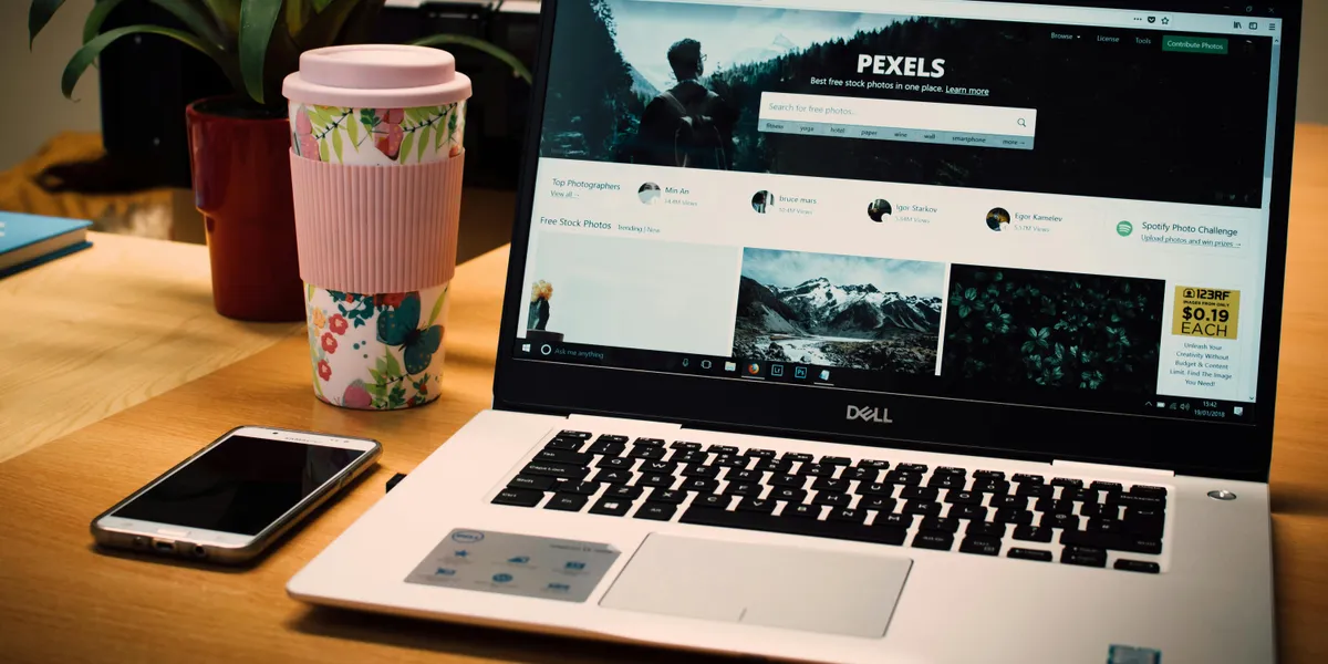 A&nbsp;tidy&nbsp;desk&nbsp;setting&nbsp;with&nbsp;a&nbsp;laptop&nbsp;showing&nbsp;a&nbsp;stock&nbsp;photo&nbsp;website&nbsp;and&nbsp;a&nbsp;smartphone.