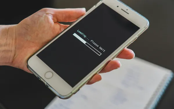 Close-up&nbsp;of&nbsp;a&nbsp;hand&nbsp;holding&nbsp;a&nbsp;smartphone&nbsp;with&nbsp;a&nbsp;loading&nbsp;screen&nbsp;displayed,&nbsp;showcasing&nbsp;technology&nbsp;usage.
