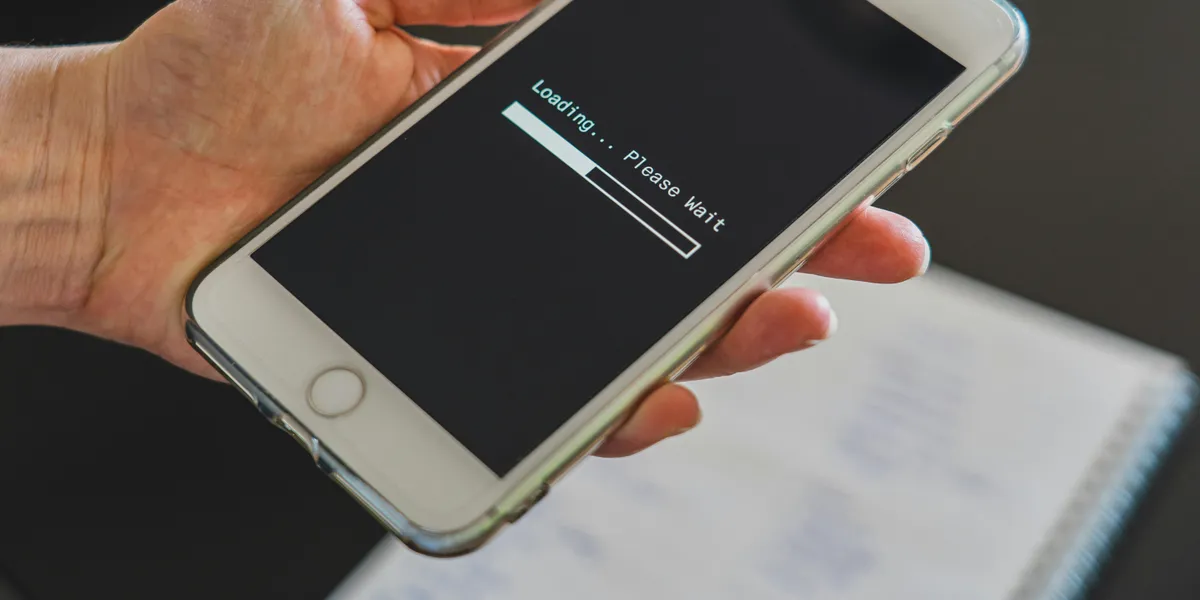 Close-up&nbsp;of&nbsp;a&nbsp;hand&nbsp;holding&nbsp;a&nbsp;smartphone&nbsp;with&nbsp;a&nbsp;loading&nbsp;screen&nbsp;displayed,&nbsp;showcasing&nbsp;technology&nbsp;usage.