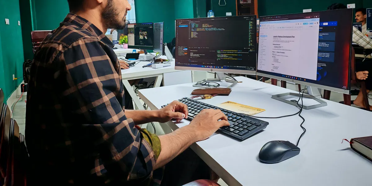 A&nbsp;software&nbsp;developer&nbsp;working&nbsp;on&nbsp;code&nbsp;at&nbsp;a&nbsp;dual&nbsp;monitor&nbsp;setup&nbsp;in&nbsp;a&nbsp;modern&nbsp;office.