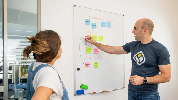 Two&nbsp;colleagues&nbsp;brainstorming&nbsp;marketing&nbsp;strategies&nbsp;on&nbsp;a&nbsp;whiteboard.
