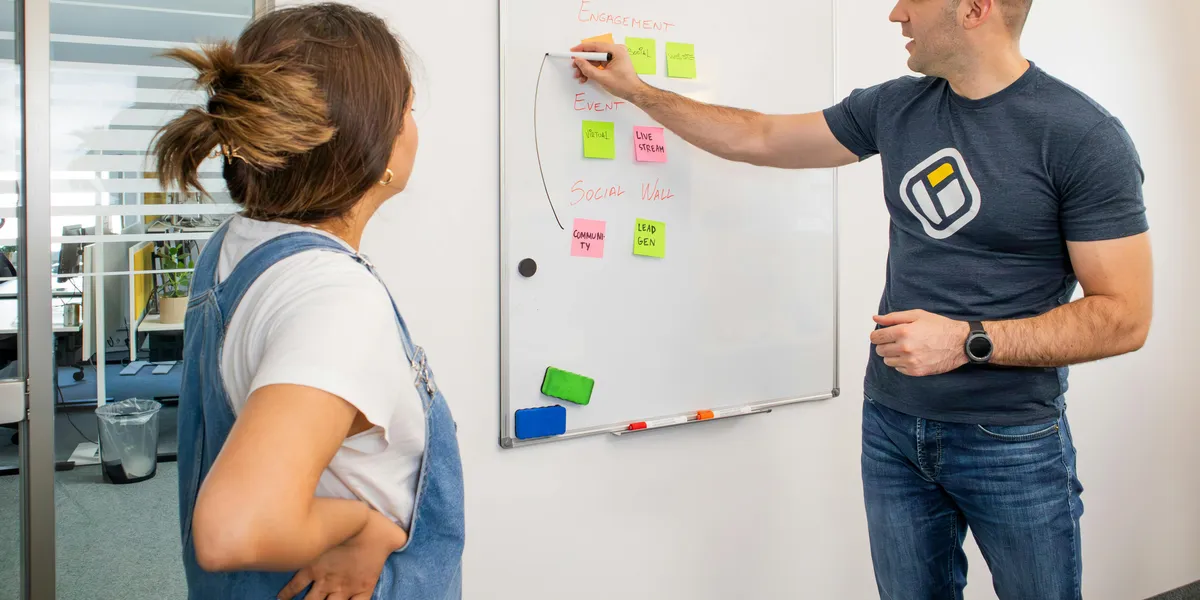Two&nbsp;colleagues&nbsp;brainstorming&nbsp;marketing&nbsp;strategies&nbsp;on&nbsp;a&nbsp;whiteboard.
