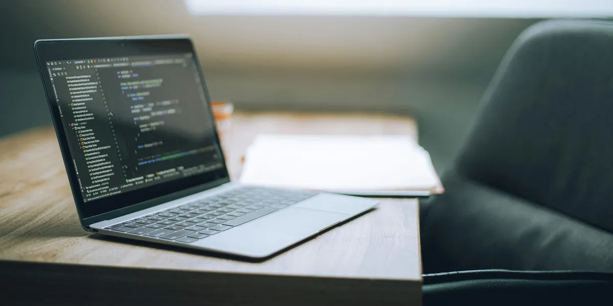 Open&nbsp;laptop&nbsp;displaying&nbsp;code&nbsp;on&nbsp;desk&nbsp;in&nbsp;bright,&nbsp;modern&nbsp;office&nbsp;setting.&nbsp;Ideal&nbsp;for&nbsp;tech&nbsp;and&nbsp;remote&nbsp;work&nbsp;context.