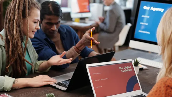 Diverse&nbsp;team&nbsp;collaborating&nbsp;with&nbsp;laptops&nbsp;in&nbsp;a&nbsp;modern&nbsp;office&nbsp;setting,&nbsp;discussing&nbsp;digital&nbsp;evolution.