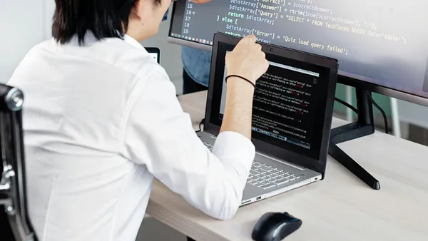 Two&nbsp;professionals&nbsp;collaborating&nbsp;on&nbsp;coding&nbsp;tasks&nbsp;in&nbsp;a&nbsp;modern&nbsp;office&nbsp;environment&nbsp;with&nbsp;laptops&nbsp;and&nbsp;monitors.