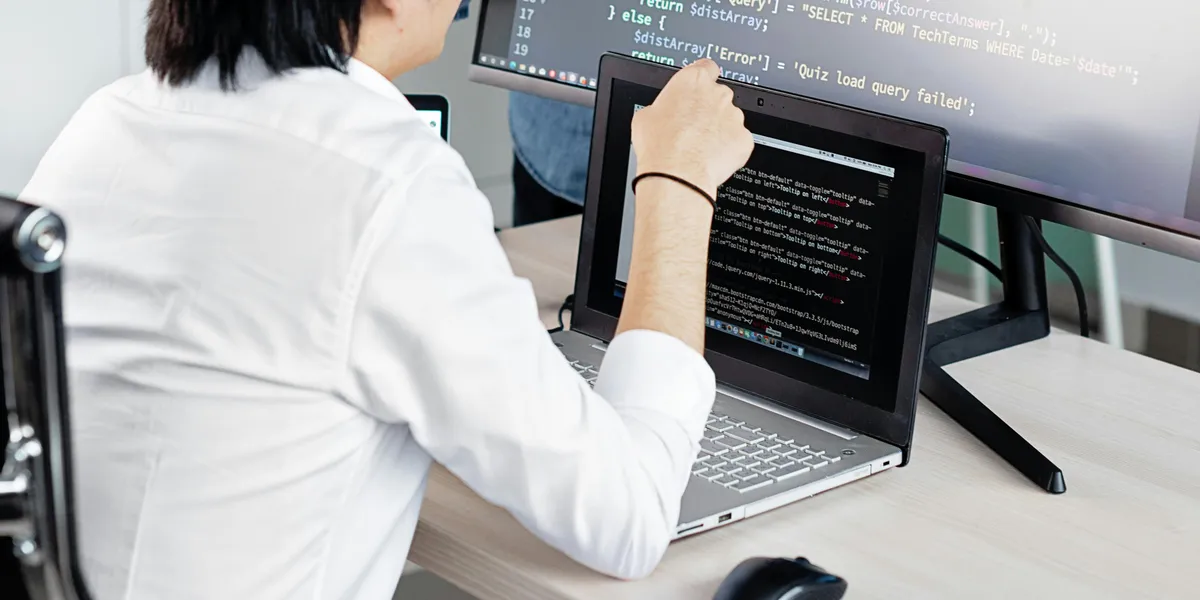 Two&nbsp;professionals&nbsp;collaborating&nbsp;on&nbsp;coding&nbsp;tasks&nbsp;in&nbsp;a&nbsp;modern&nbsp;office&nbsp;environment&nbsp;with&nbsp;laptops&nbsp;and&nbsp;monitors.