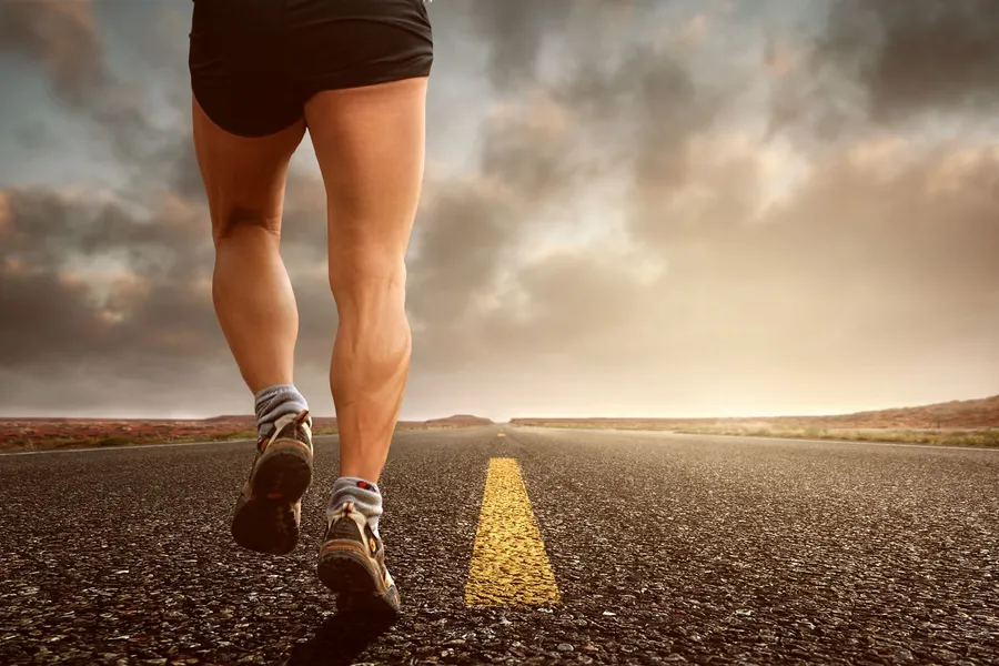 Runner's&nbsp;legs&nbsp;on&nbsp;a&nbsp;road&nbsp;during&nbsp;a&nbsp;sunset,&nbsp;symbolizing&nbsp;endurance&nbsp;and&nbsp;outdoor&nbsp;fitness&nbsp;training.