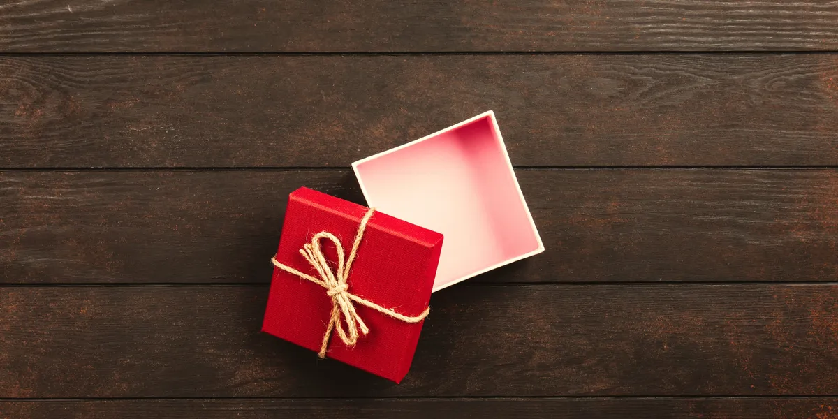 Top&nbsp;view&nbsp;of&nbsp;an&nbsp;open&nbsp;red&nbsp;gift&nbsp;box&nbsp;tied&nbsp;with&nbsp;twine&nbsp;on&nbsp;a&nbsp;wooden&nbsp;surface.