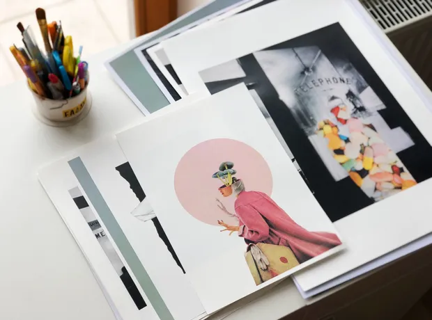 Colorful&nbsp;art&nbsp;prints&nbsp;and&nbsp;photographs&nbsp;spread&nbsp;across&nbsp;a&nbsp;desk