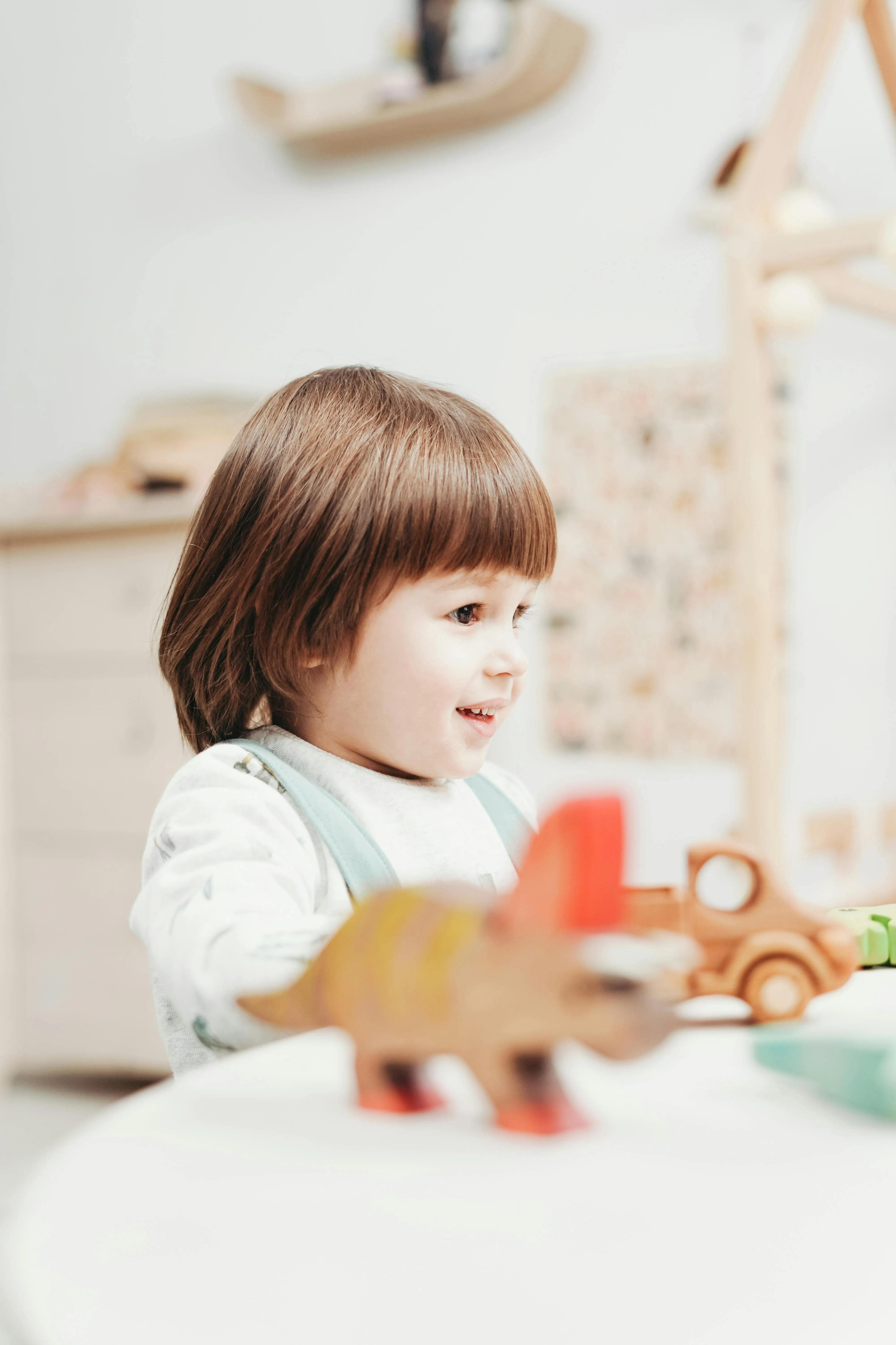 A&nbsp;joyful&nbsp;child&nbsp;engages&nbsp;with&nbsp;wooden&nbsp;toys&nbsp;in&nbsp;an&nbsp;indoor&nbsp;playroom&nbsp;setting.