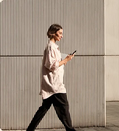 Woman walking past a ribbed wall while checking her phone