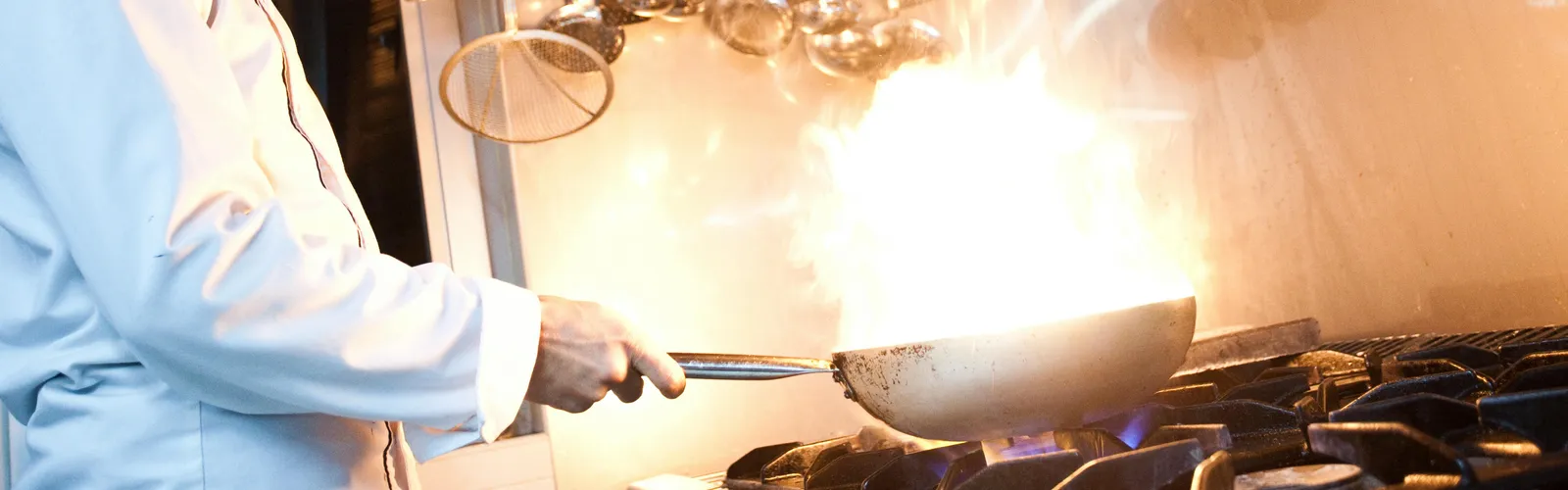 Dynamic&nbsp;shot&nbsp;of&nbsp;a&nbsp;chef&nbsp;flambéing&nbsp;a&nbsp;dish&nbsp;with&nbsp;skill&nbsp;and&nbsp;focus&nbsp;in&nbsp;a&nbsp;professional&nbsp;kitchen&nbsp;setting.