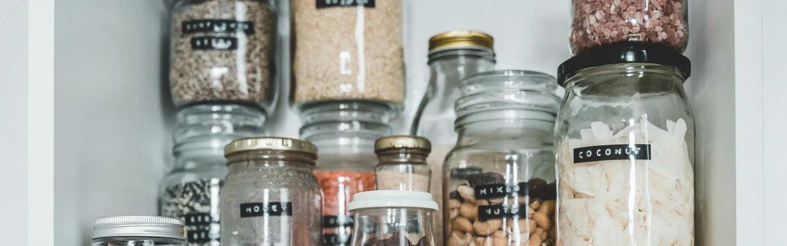 Clean&nbsp;pantry&nbsp;shelves&nbsp;displaying&nbsp;various&nbsp;food&nbsp;items&nbsp;stored&nbsp;in&nbsp;labeled&nbsp;glass&nbsp;jars.