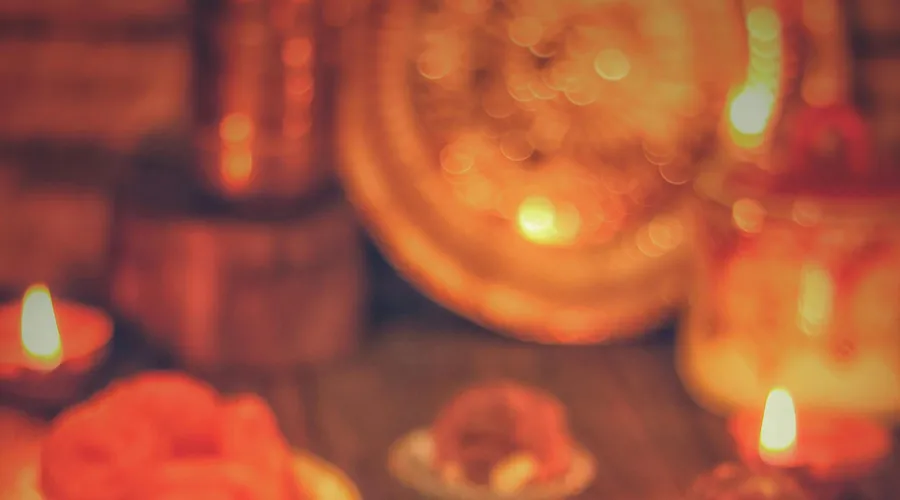 A&nbsp;warm&nbsp;display&nbsp;of&nbsp;Indian&nbsp;sweets&nbsp;and&nbsp;diyas&nbsp;celebrating&nbsp;a&nbsp;festive&nbsp;occasion&nbsp;indoors.