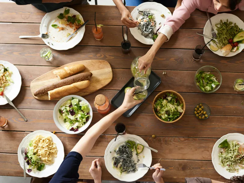 An&nbsp;overhead&nbsp;shot&nbsp;of&nbsp;a&nbsp;dining&nbsp;table&nbsp;featuring&nbsp;various&nbsp;pasta&nbsp;dishes&nbsp;and&nbsp;salads&nbsp;shared&nbsp;by&nbsp;a&nbsp;group.