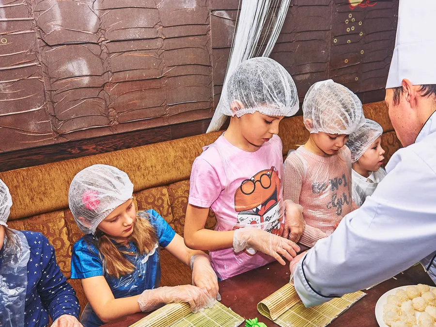 Kids&nbsp;and&nbsp;adults&nbsp;smiling&nbsp;while&nbsp;chopping&nbsp;vegetables&nbsp;during&nbsp;a&nbsp;nutrition&nbsp;education&nbsp;class.