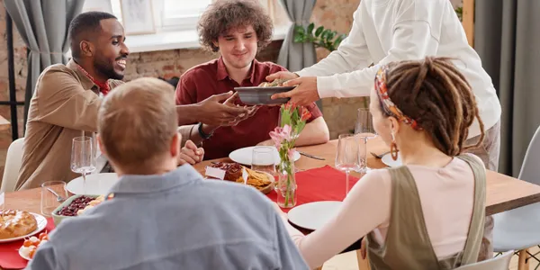 Community&nbsp;members&nbsp;of&nbsp;different&nbsp;ages&nbsp;and&nbsp;backgrounds&nbsp;sitting&nbsp;together&nbsp;around&nbsp;a&nbsp;table&nbsp;filled&nbsp;with&nbsp;food.