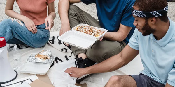 Community&nbsp;members&nbsp;of&nbsp;different&nbsp;ages&nbsp;and&nbsp;backgrounds&nbsp;sitting&nbsp;together&nbsp;around&nbsp;a&nbsp;table&nbsp;filled&nbsp;with&nbsp;food.