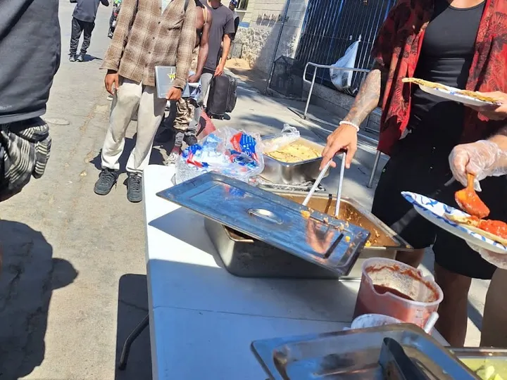 SciCook&nbsp;volunteers&nbsp;serving&nbsp;free&nbsp;hot&nbsp;meals&nbsp;from&nbsp;an&nbsp;outdoor&nbsp;table&nbsp;to&nbsp;community&nbsp;members&nbsp;in&nbsp;San&nbsp;Diego