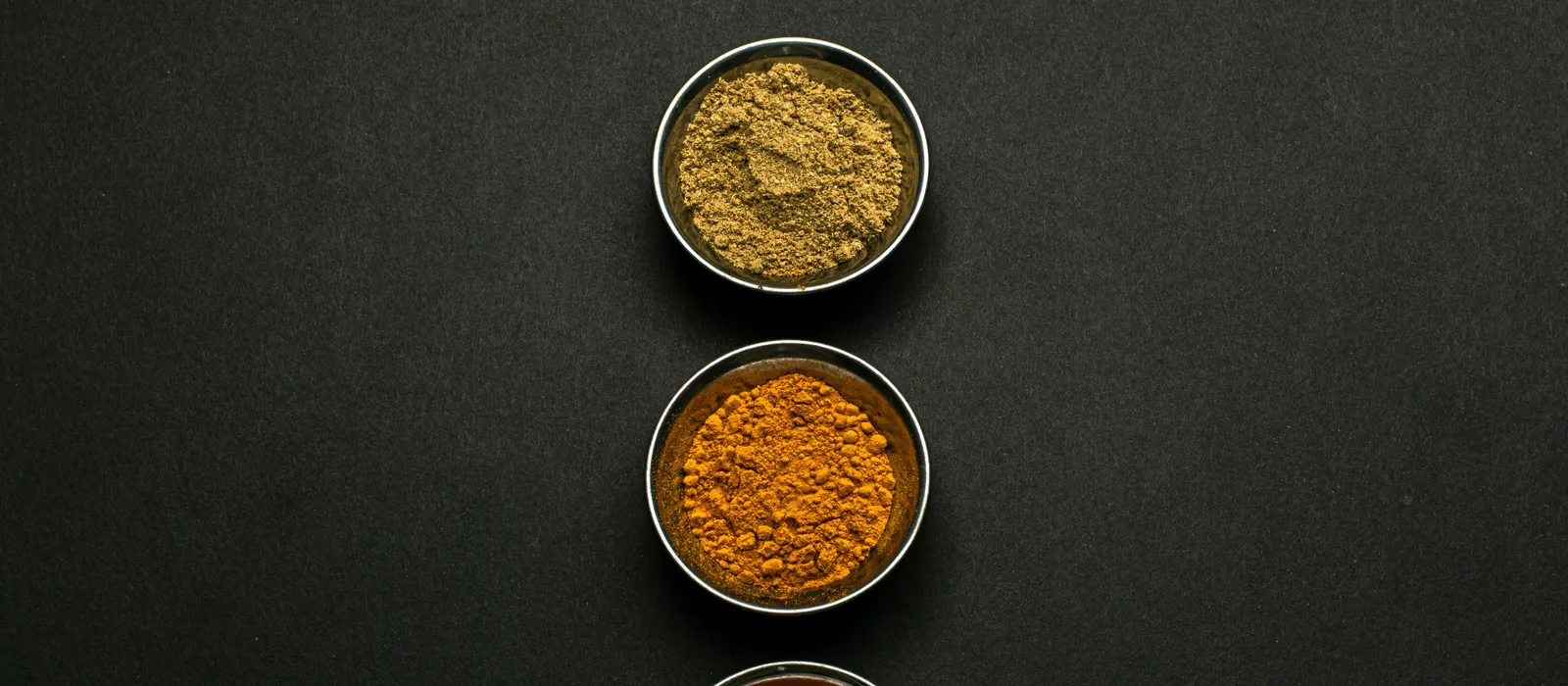 Top&nbsp;view&nbsp;of&nbsp;assorted&nbsp;spice&nbsp;powders&nbsp;in&nbsp;metal&nbsp;bowls&nbsp;showcasing&nbsp;vibrant&nbsp;colors&nbsp;against&nbsp;a&nbsp;dark&nbsp;background.