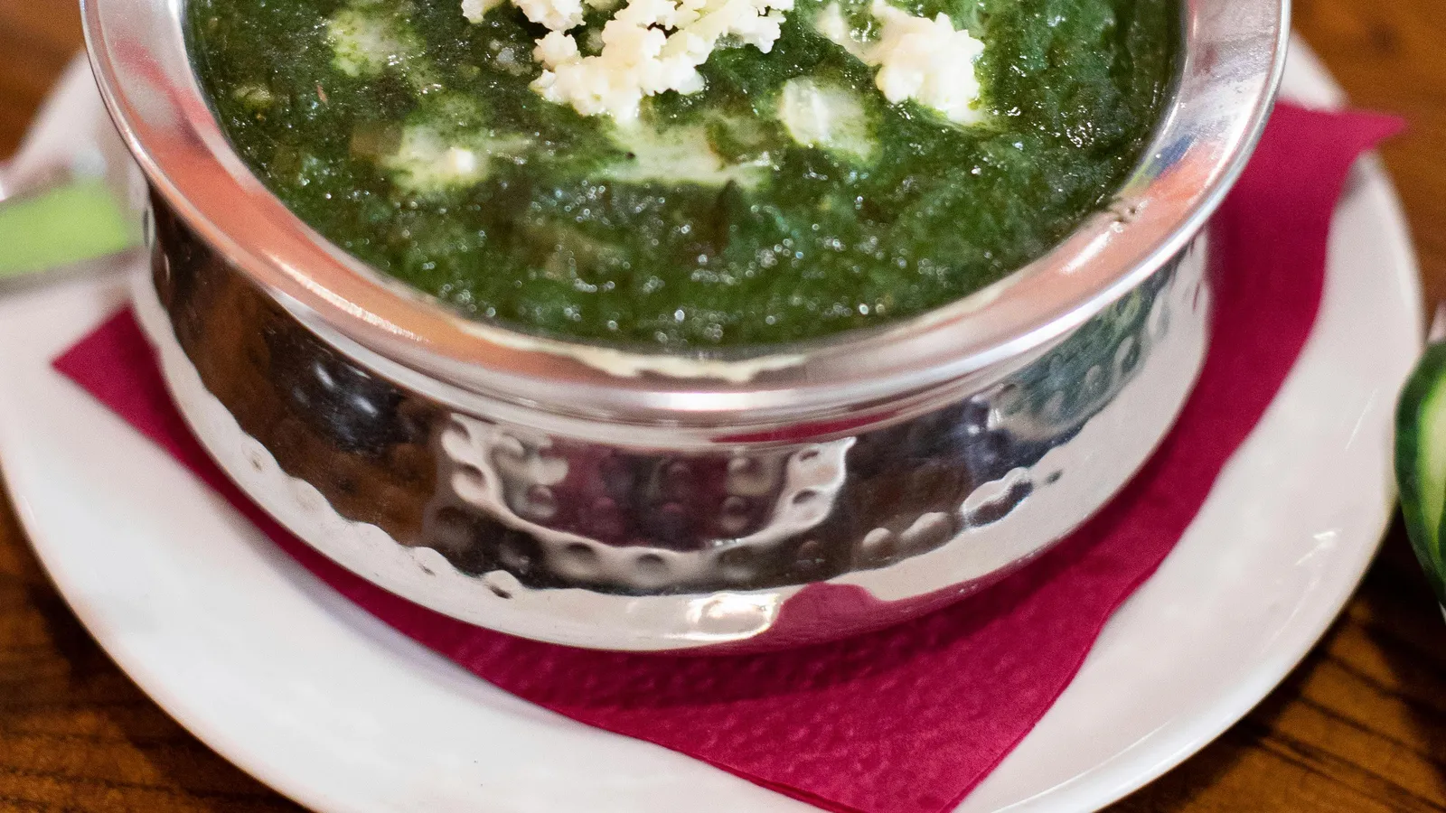Top-down&nbsp;view&nbsp;of&nbsp;creamy&nbsp;palak&nbsp;paneer&nbsp;served&nbsp;in&nbsp;a&nbsp;stainless&nbsp;steel&nbsp;bowl,&nbsp;garnished&nbsp;with&nbsp;crumbled&nbsp;cheese.