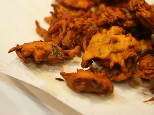 Golden&nbsp;brown&nbsp;Indian&nbsp;pakoras&nbsp;freshly&nbsp;fried&nbsp;and&nbsp;resting&nbsp;on&nbsp;paper&nbsp;towel&nbsp;in&nbsp;kitchen&nbsp;setting.