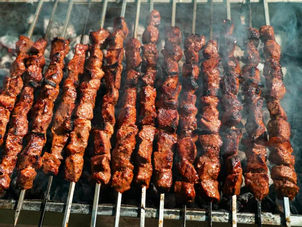 Juicy&nbsp;beef&nbsp;skewers&nbsp;sizzling&nbsp;on&nbsp;an&nbsp;open&nbsp;charcoal&nbsp;grill,&nbsp;perfect&nbsp;for&nbsp;summer&nbsp;BBQ.