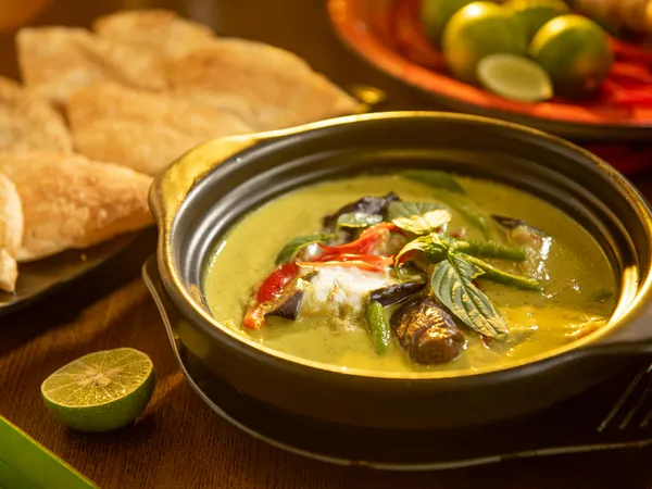 A&nbsp;flavorful&nbsp;Thai&nbsp;green&nbsp;curry&nbsp;with&nbsp;vegetables&nbsp;and&nbsp;aromatic&nbsp;herbs&nbsp;in&nbsp;a&nbsp;stylish&nbsp;black&nbsp;bowl.