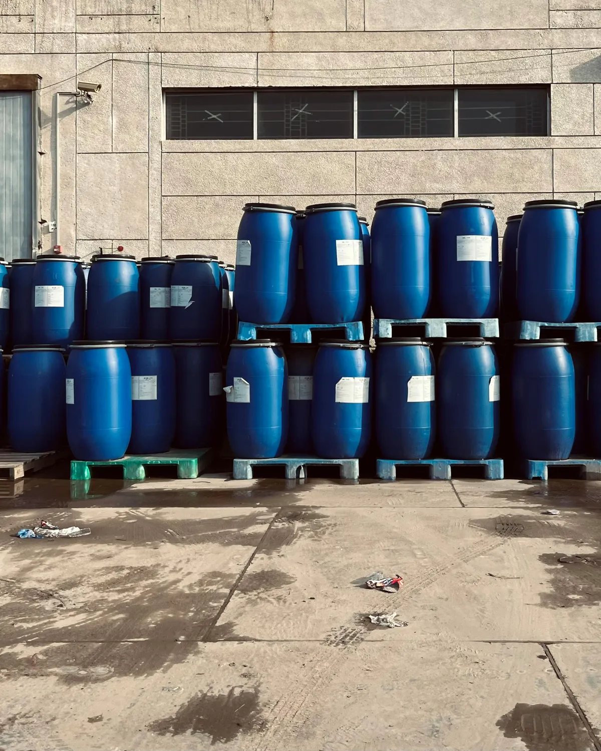 Blue industrial drums stored outside a manufacturing building