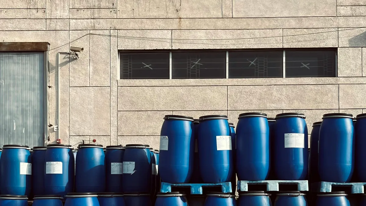 Blue industrial drums stored outside a manufacturing building