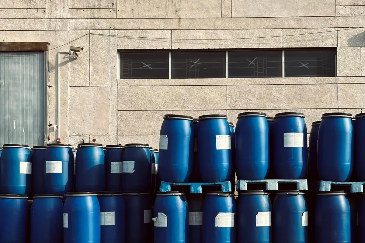 Blue industrial drums stored outside a manufacturing building