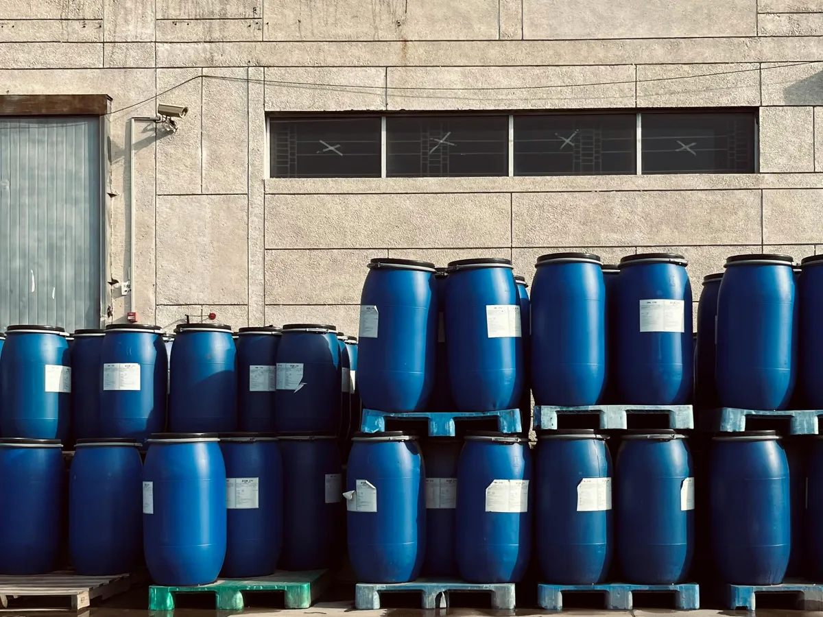 Blue industrial drums stored outside a manufacturing building